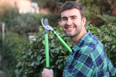 Bahçede çalıları kesen yakışıklı genç adamın yakın plan portresi.