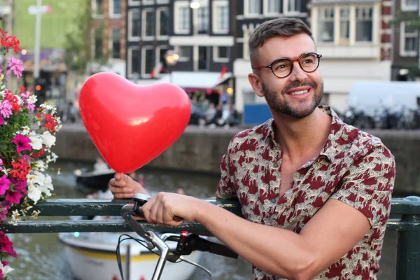 Hip man holding heart shaped balloon in Amsterdam