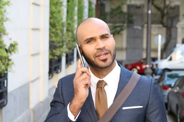 Cute ethnic businessman calling by phone outdoors