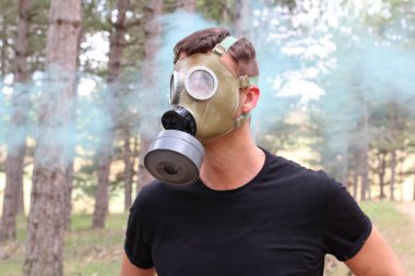 Ormanda gaz maskesi takan adam.
