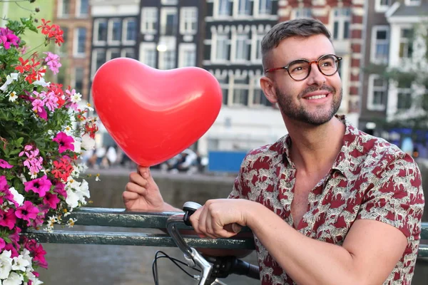 Hip man holding heart shaped balloon in Amsterdam