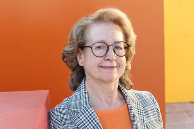 Gözlüklü, gülümseyen yaşlı bir kadının portresi.