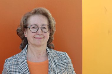 Gözlüklü gülümseyen yaşlı kadının portresi.