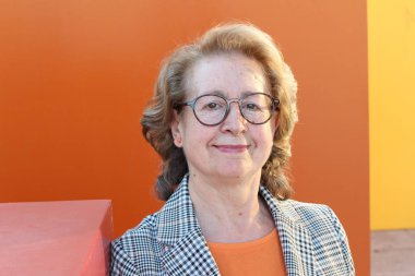 Gözlüklü, gülümseyen yaşlı bir kadının portresi.