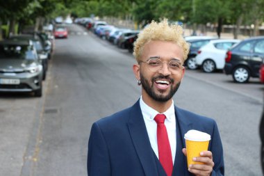 Takım elbiseli yakışıklı genç işadamının sokakta bir fincan kağıt kahveyle yakın plan portresi.