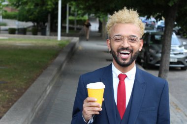 Takım elbiseli yakışıklı genç işadamının sokakta bir fincan kağıt kahveyle yakın plan portresi.