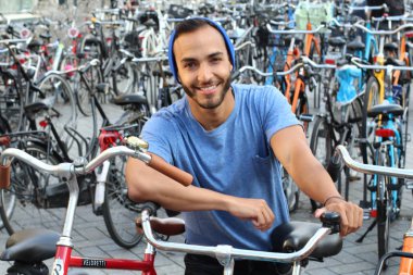 Eski Avrupa şehrinde bisiklet parkındaki yakışıklı genç adamın yakın plan portresi.