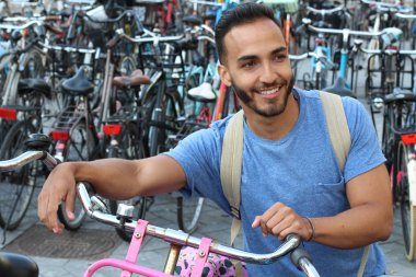 Eski Avrupa şehrinde bisiklet parkındaki yakışıklı genç adamın yakın plan portresi.