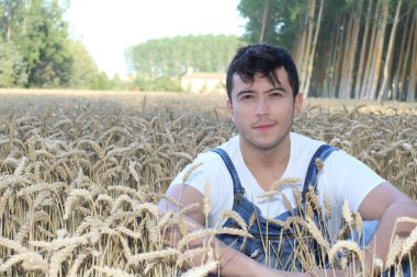 Buğday tarlasında yakışıklı etnik çiftçi