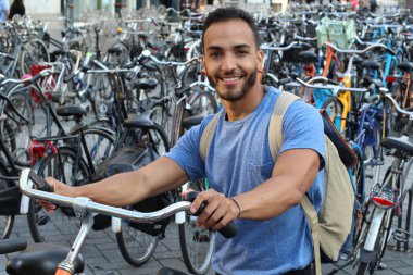 Eski Avrupa şehrinde bisiklet parkındaki yakışıklı genç adamın yakın plan portresi.