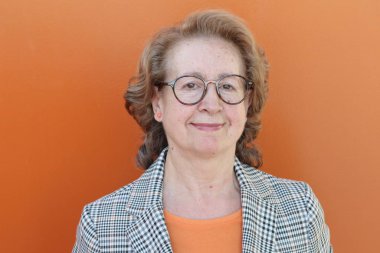 Gözlüklü, gülümseyen yaşlı bir kadının portresi.