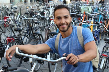 Eski Avrupa şehrinde bisiklet parkındaki yakışıklı genç adamın yakın plan portresi.