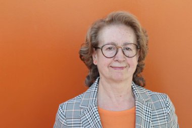 Gözlüklü, gülümseyen yaşlı bir kadının portresi.