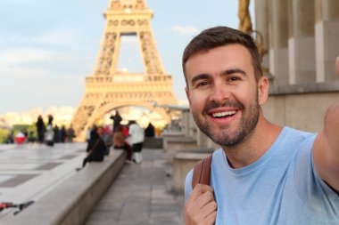Mutlu genç adam Eyfel Kulesi, Paris 'te selfie çekiyor.