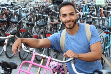 Eski Avrupa şehrinde bisiklet parkındaki yakışıklı genç adamın yakın plan portresi.