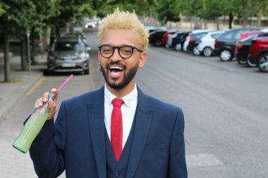 Takım elbiseli yakışıklı genç işadamının sokakta limonata şişesiyle yakın plan portresi.