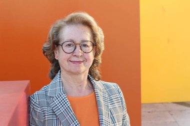 Gözlüklü, gülümseyen yaşlı bir kadının portresi.