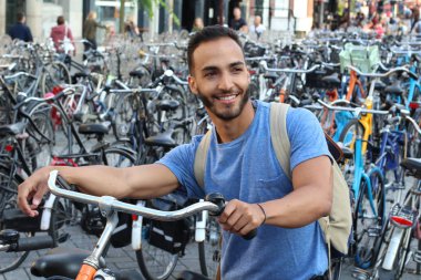 Eski Avrupa şehrinde bisiklet parkındaki yakışıklı genç adamın yakın plan portresi.