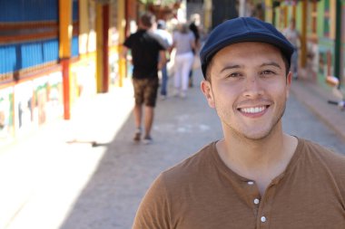 Şapka takan genç bir İspanyol. Gündüz vakti sokakta dikilen adam 