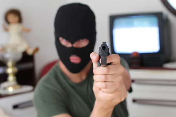 close-up portrait of man in mask with gun aiming at camera