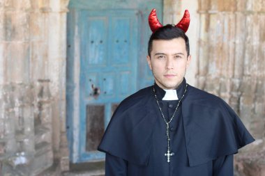 Kilise arka planında kırmızı boynuz takan cüppeli şeytan rahip.