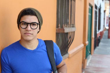 Gözlüklü, sokakta sırt çantalı yakışıklı bir gencin yakın plan portresi.