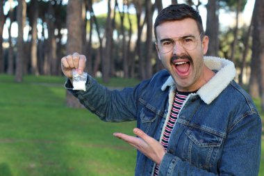 Genç adam elinde beyaz toz paketi tutuyor.