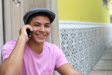 Yakından çekilmiş, şık giyinmiş, sokakta telefonla konuşan yakışıklı bir genç portresi.