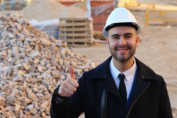 Young businessman in helmet on construction background