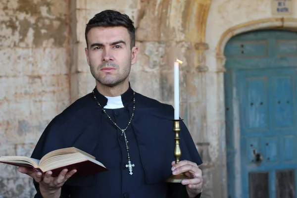 Serious Priest Holding Open Bible Burning Candle Church Background — Stock Photo, Image