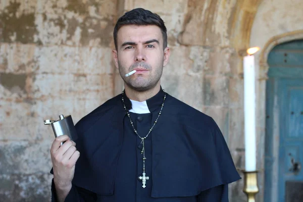 在教堂的背景下 在燃烧的蜡烛前 牧师吸烟和饮酒 — 图库照片