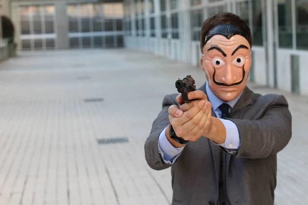 Elegant businessman with wearing mask holding gun outdoors at daytime