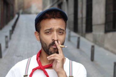 Sokakta sigara içen yakışıklı bir gencin yakın plan portresi.