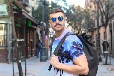 Mor gömlekli ve güneş gözlüklü yakışıklı genç adamın yakın plan portresi.