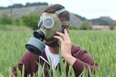 Gaz maskeli bir adam doğadan arıyor.