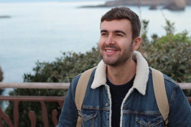 Deniz kıyısında şık giyinmiş yakışıklı bir gencin yakın plan portresi.