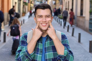 Ekose gömlekli yakışıklı genç adamın yakın plan portresi. Sokakta somurtuyor.