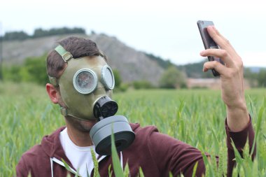 Gaz maskeli bir adam doğadan arıyor.