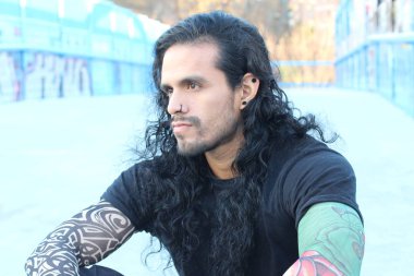 Sahte dövmeleri ve uzun saçları olan yakışıklı bir gencin yakın plan portresi.