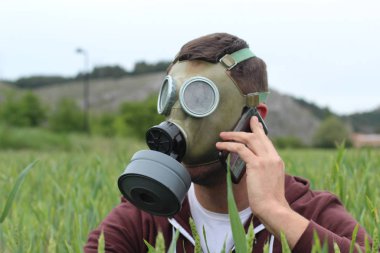 Gaz maskeli bir adam doğadan arıyor.