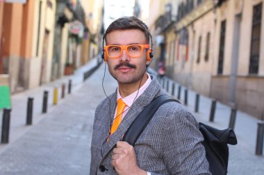 Ceketli, kulaklıklı ve gözlüklü yakışıklı bir adamın yakın plan portresi.