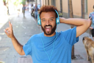 Sokaklarda kulaklıkla müzik dinleyen yakışıklı bir gencin yakın plan portresi.