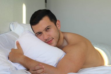 Yakışıklı etnik adam yatakta üstsüz.