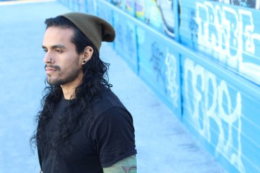 Sahte dövmeleri ve uzun saçları olan yakışıklı bir gencin yakın plan portresi.