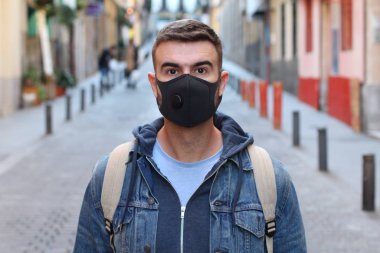Sokakta koruyucu maskeli yakışıklı bir gencin yakın plan portresi.