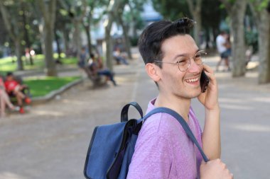 Parkta telefonla konuşan şık elbiseli yakışıklı bir gencin yakın plan portresi.