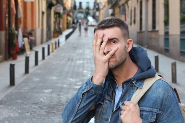 Yakışıklı genç adamın yakın plan portresi. Sokakta eli yüzü kaplayan.