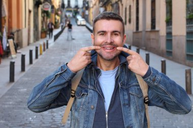 Sokakta yüzünü buruşturan kot ceketli yakışıklı genç adamın yakın plan portresi.