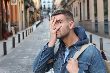 Yakışıklı genç adamın yakın plan portresi. Sokakta eli yüzü kaplayan.