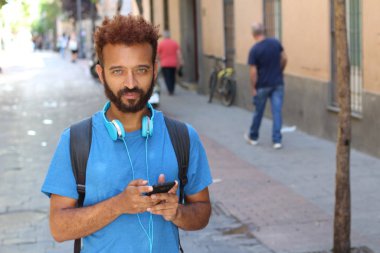 Sokaklarda kulaklıkla müzik dinleyen yakışıklı bir gencin yakın plan portresi.